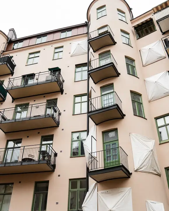 Fasad med gröna fönster under pågående underhåll. Herrängens Måleriteknik utför fönstermålning för att skydda karmar och bågar mot slitage.